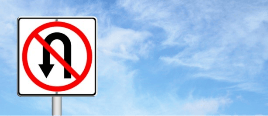 A no U-turn traffic sign with a red circle and diagonal line over a U-turn symbol against a blue sky background.