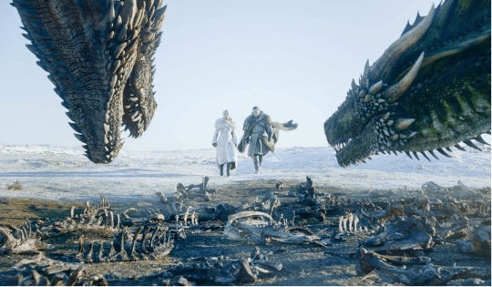 A dramatic scene featuring two characters walking through a snowy landscape, flanked by two large dragons, with skeletal remains scattered on the ground.