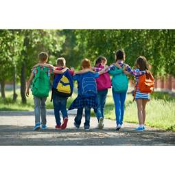 A group of six children walking together along a path, wearing colorful backpacks and embracing each other while enjoying a sunny day outdoors.